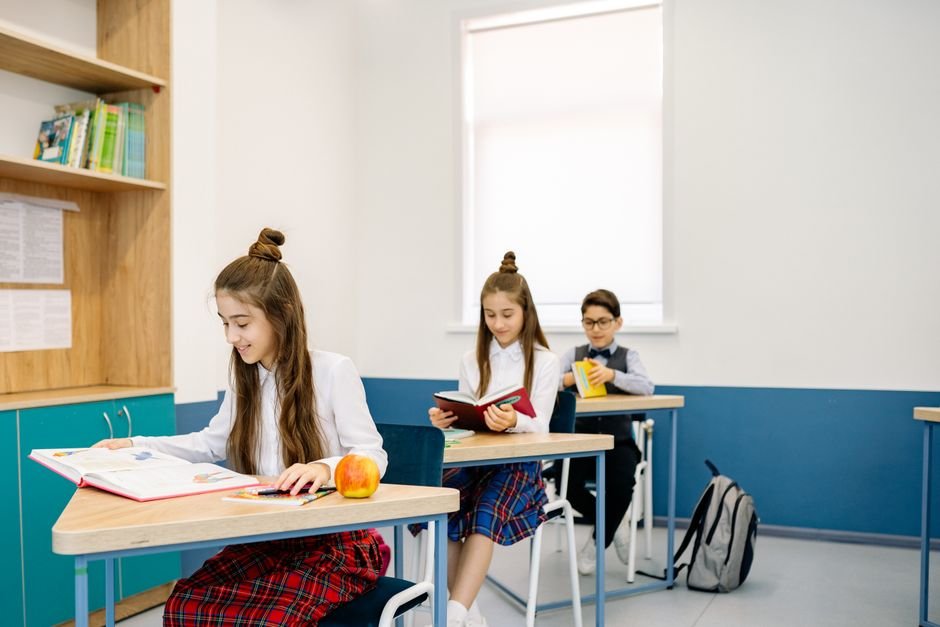 馬來西亞 國際學校 選體系 — Three children studying at desks in a bright, modern classro